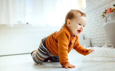 happy-child-in-orange-sweater-plays-with-feather-on-the-floor